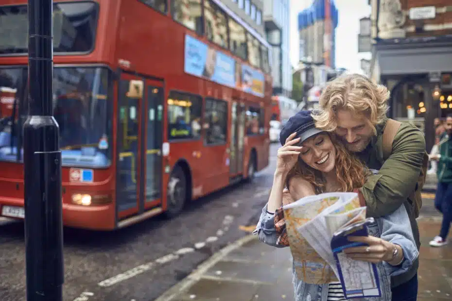 Junges Paar mit Stadtplan vor einem London Bus auf einer ihrer Staedtereisen